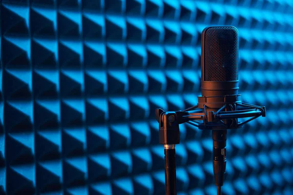 Micrófono de condensador de estudio sobre fondo de panel de espuma acústica azul — Foto de Stock
