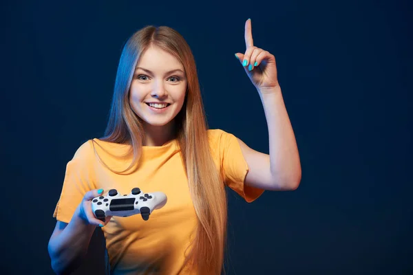 游戏女孩 兴奋的女孩拿着游戏操纵杆指着手指 蓝色背景 — 图库照片