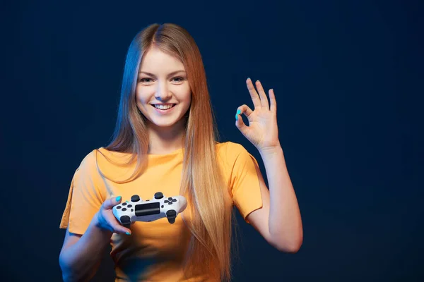 游戏女孩 快乐的女孩拿着显示Ok标志的电子游戏控制杆 蓝色背景 — 图库照片