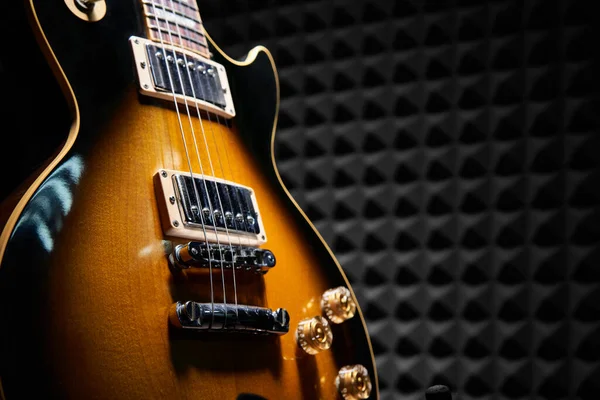 アコースティックフォームパネルの上に立つサンバーストエレクトリックギターの閉鎖背景 — ストック写真
