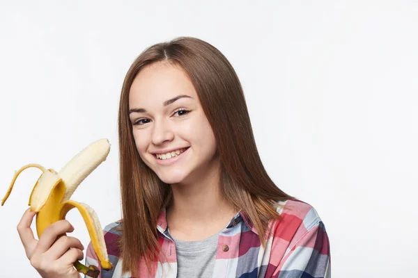 Портрет дівчинки-підлітка, що тримає наполовину очищений банан — стокове фото