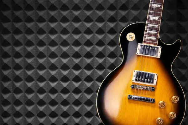 アコースティックフォームパネルの背景に立つサンバーストエレクトリックギター — ストック写真