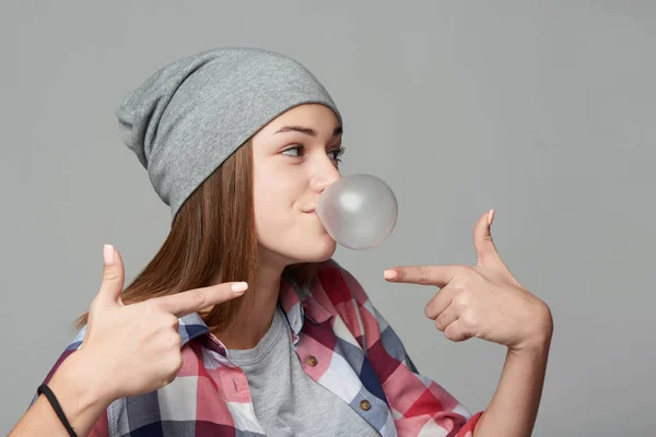 Una niña sonriente que sopla una burbuja que mira hacia otro lado. — Foto de Stock