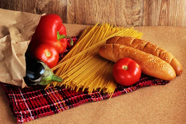 Food photo. Grocery shopping. Package of fresh vegetables. Spaghetti. Wood backround.