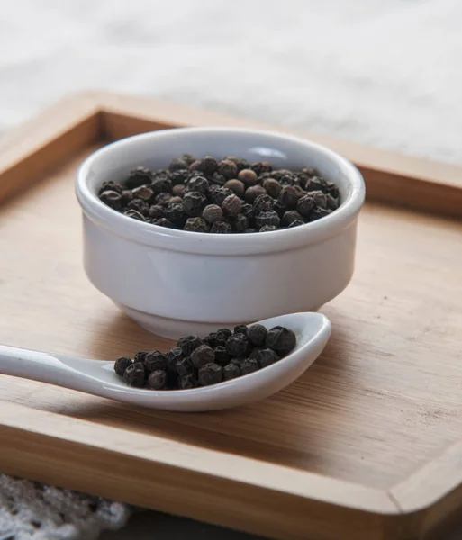 Black pepper on wood background — Stock Photo, Image