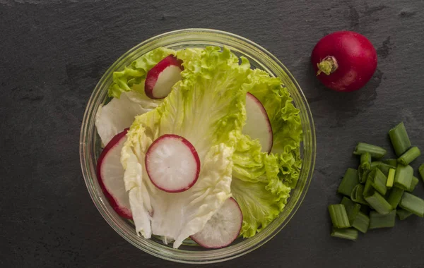 Fresh radish salad with lettuce leaves in glass bowl, close-up