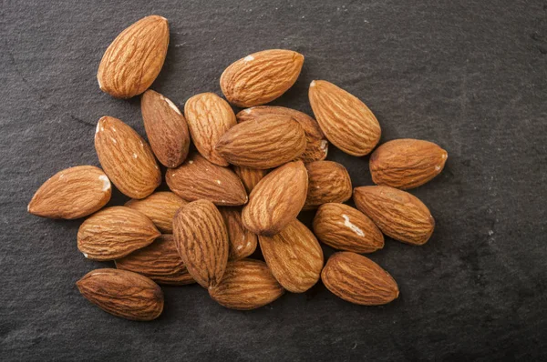 Almonds in a black plate. Close-up. — Stock Photo, Image