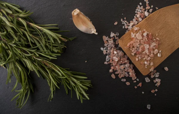 Salt, peppar, vitlök och rosmarin på en skärbräda — Stockfoto