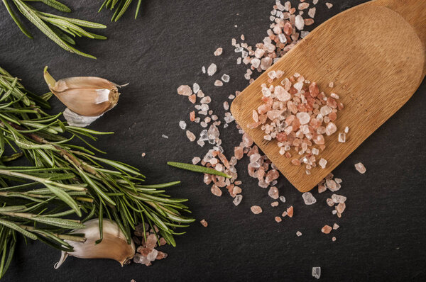 Salt, pepper, garlic and rosemary on a chopping board