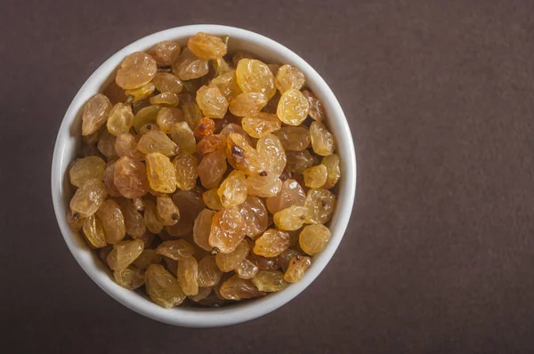 Raisins in saucer on wooden table, closeup — Stock Photo, Image