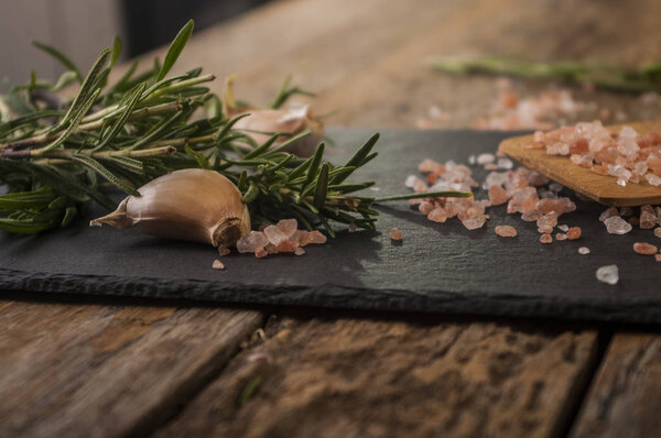 Salt, pepper, garlic and rosemary on a chopping board
