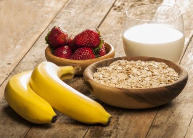 Sağlıklı kahvaltı konsepti ile yulaf gevreği ve rustik arka plan üzerinde taze çilek. Gıda granola ve musli yapılmış. Böğürtlen, bal ve süt ile sağlıklı muz smoothie.