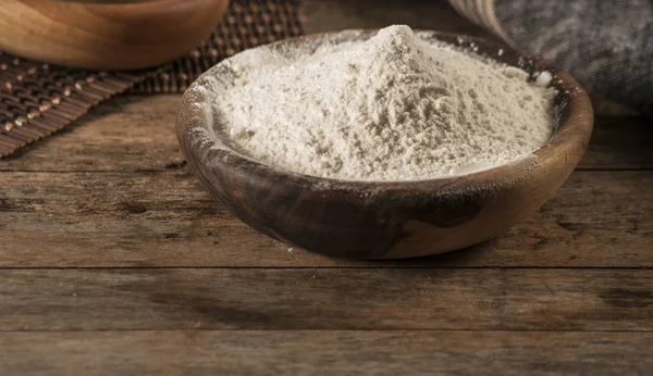 Flour in a wooden bowl, paper bag and spoon. Top view, space for text. — Stock Photo, Image