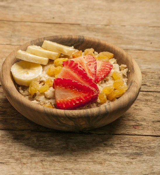 Oatmeal porridge with strawberry and banana in wood bowl — Stock Photo, Image