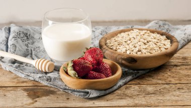 Sağlıklı kahvaltı konsepti ile yulaf gevreği ve rustik arka plan üzerinde taze çilek. Gıda granola ve musli yapılmış. Böğürtlen, bal ve süt ile sağlıklı muz smoothie.