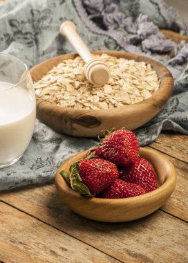 Sağlıklı kahvaltı konsepti ile yulaf gevreği ve rustik arka plan üzerinde taze çilek. Gıda granola ve musli yapılmış. Böğürtlen, bal ve süt ile sağlıklı muz smoothie.