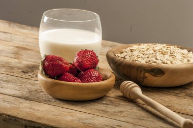 Sağlıklı kahvaltı konsepti ile yulaf gevreği ve rustik arka plan üzerinde taze çilek. Gıda granola ve musli yapılmış. Böğürtlen, bal ve süt ile sağlıklı muz smoothie.