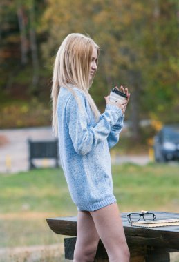 Sonbahar kadın kahve içme. Genç kadının tek kullanımlık kahve Kupası sonbahar ortamındaki sıcak içecek kavramı düşmek.