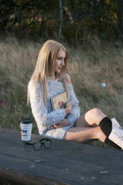 Sonbahar kadın kahve içme. Genç kadının tek kullanımlık kahve Kupası sonbahar ortamındaki sıcak içecek kavramı düşmek.