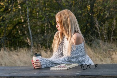 Sonbahar kadın kahve içme. Genç kadının tek kullanımlık kahve Kupası sonbahar ortamındaki sıcak içecek kavramı düşmek.