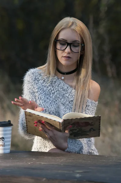 Autumn woman drinking coffee. Fall concept of young woman enjoying hot drink from disposable coffee cup in fall landscape.