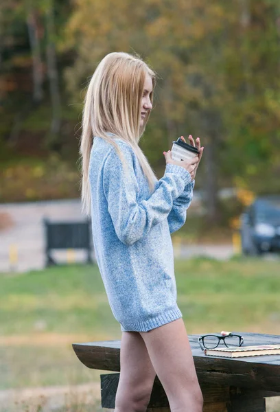 Sonbahar kadın kahve içme. Genç kadının tek kullanımlık kahve Kupası sonbahar ortamındaki sıcak içecek kavramı düşmek.