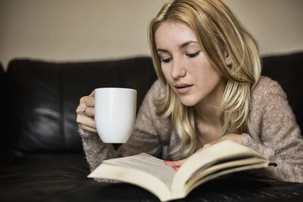 Жінка читає книгу і п'є каву — стокове фото