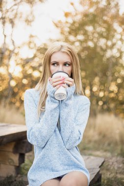 Sonbahar kadın kahve içme. Genç kadının tek kullanımlık kahve Kupası sonbahar ortamındaki sıcak içecek kavramı düşmek.