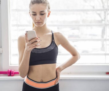 Genç kadın spor salonunda smartphone kullanarak yerleştirmek