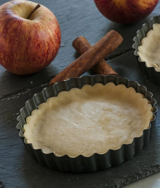 Work with the dough. Form for baking and ingredients for apple pie. The process of preparation of apple tart. View from above. Flat lay.