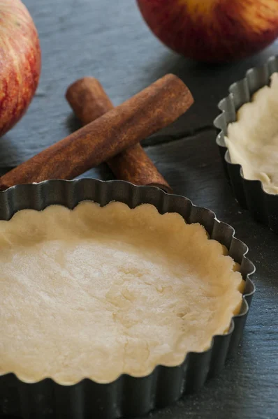 Work with the dough. Form for baking and ingredients for apple pie. The process of preparation of apple tart. View from above. Flat lay. — Stock Photo, Image