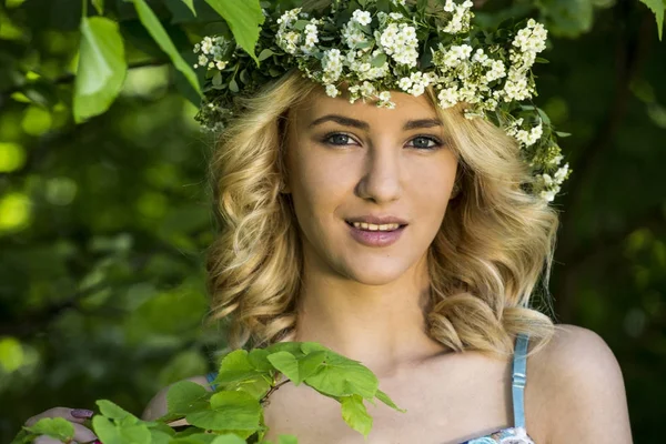 Retrato de uma bela menina sorridente sexy com uma coroa de flores em sua cabeça no parque da primavera — Fotografia de Stock