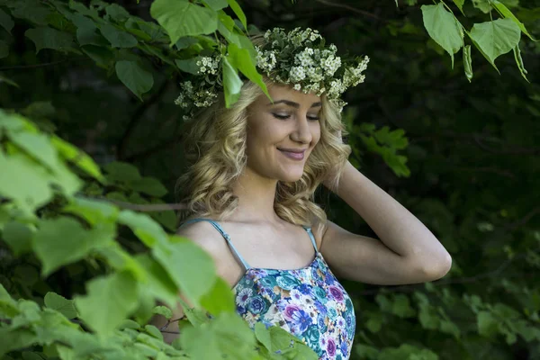 Retrato de uma bela menina sorridente sexy com uma coroa de flores em sua cabeça no parque da primavera — Fotografia de Stock