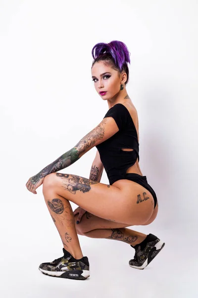 Hermosa mujer joven con el pelo carmesí elegante y tatuaje en su cuerpo posando sobre fondo grunge oscuro. Colorante capilar. Cosméticos, maquillaje. Tatuaje . —  Fotos de Stock