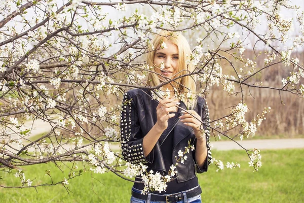 Vacker glad ung kvinna njuter av lukt i en blommande vårträdgård — Stockfoto