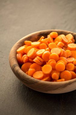 Ahşap kase havuç dilimleri. Taze gevrek slivers Daucus carota, bir kök sebze turuncu renk ile kesti. Yenilebilir taproot adet. İzole makro gıda fotoğraf yakın çekim yukarıdan