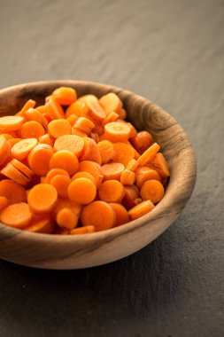 Ahşap kase havuç dilimleri. Taze gevrek slivers Daucus carota, bir kök sebze turuncu renk ile kesti. Yenilebilir taproot adet. İzole makro gıda fotoğraf yakın çekim yukarıdan