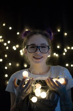 Gülümseyen ve çelenk ışıkların konuşmak güzel genç kadın 