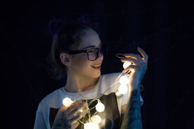 Gülümseyen ve çelenk ışıkların konuşmak güzel genç kadın 