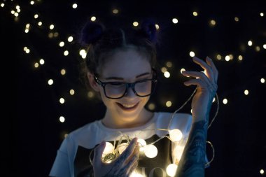 Gülümseyen ve çelenk ışıkların konuşmak güzel genç kadın 