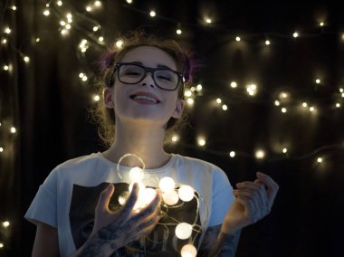 Gülümseyen ve çelenk ışıkların konuşmak güzel genç kadın 