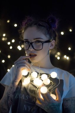 Gülümseyen ve çelenk ışıkların konuşmak güzel genç kadın 