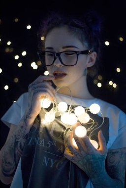 Gülümseyen ve çelenk ışıkların konuşmak güzel genç kadın 