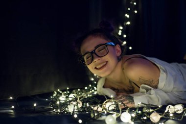 Gülümseyen ve çelenk ışıkların konuşmak güzel genç kadın 