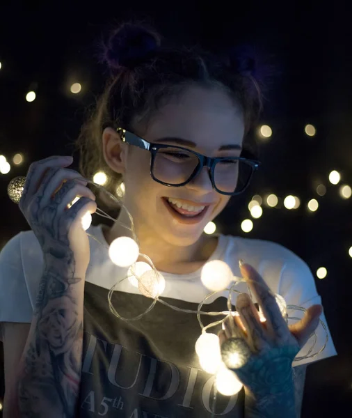 Gülümseyen ve çelenk ışıkların konuşmak güzel genç kadın 