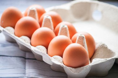 Beyaz ahşap arka planda yumurta kutusundaki çiğ tavuk yumurtalarının yakın plan görüntüsü