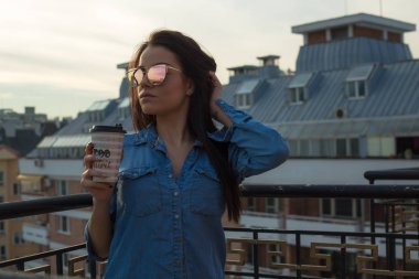 Balkonda kahve fincanı tutan genç kadın 