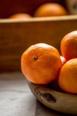 Olgun mandarin ahşap masa üzerinde narenciye ile seramik kase yakın çekim 