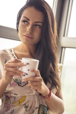 Kadın kahve içiyor, sabah dinleniyor.