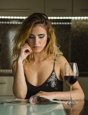 Evde bir kadeh şarapla çekici genç bir kadın.